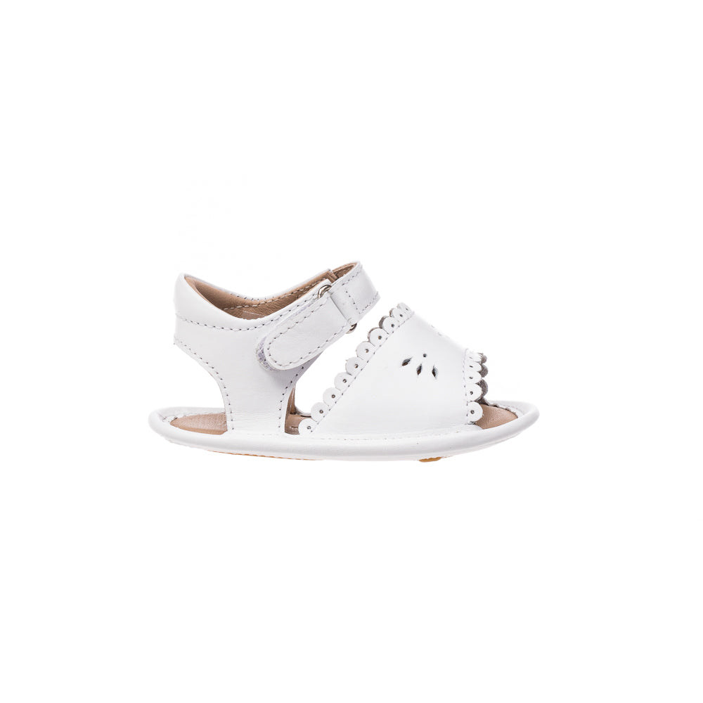 White baby sandal with scalloped edges and cutout floral details, adjustable hook-and-loop strap.
