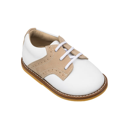 White toddler shoe with ivory perforated side panels, brown sole, and white laces.