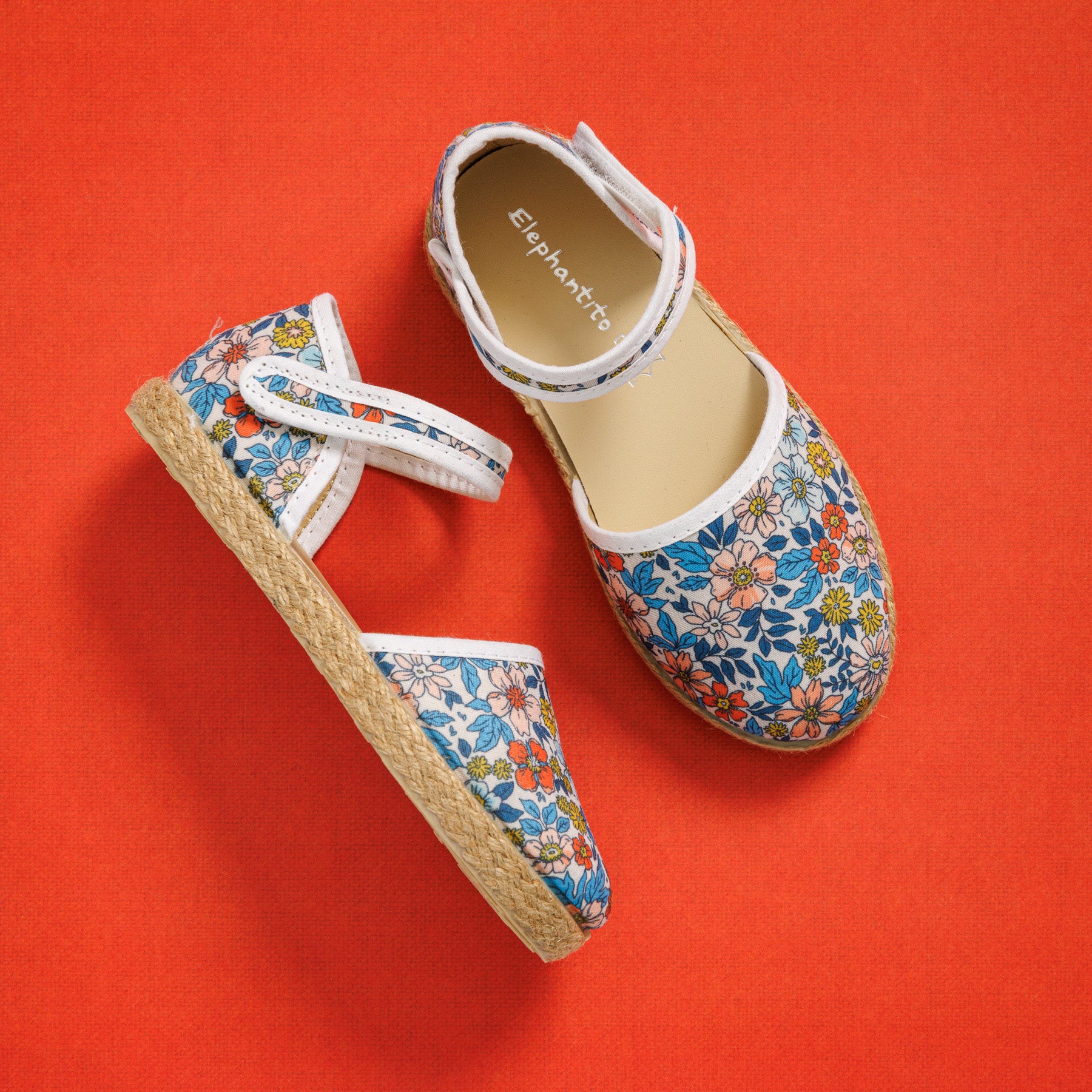 Elephantito - Girls' linen espadrille sandals with multicolor floral print and jute-wrapped soles on orange background.