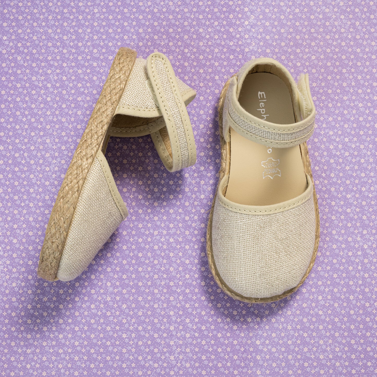 Metallic white linen espadrille for girls with ankle strap and braided jute sole on purple patterned background.