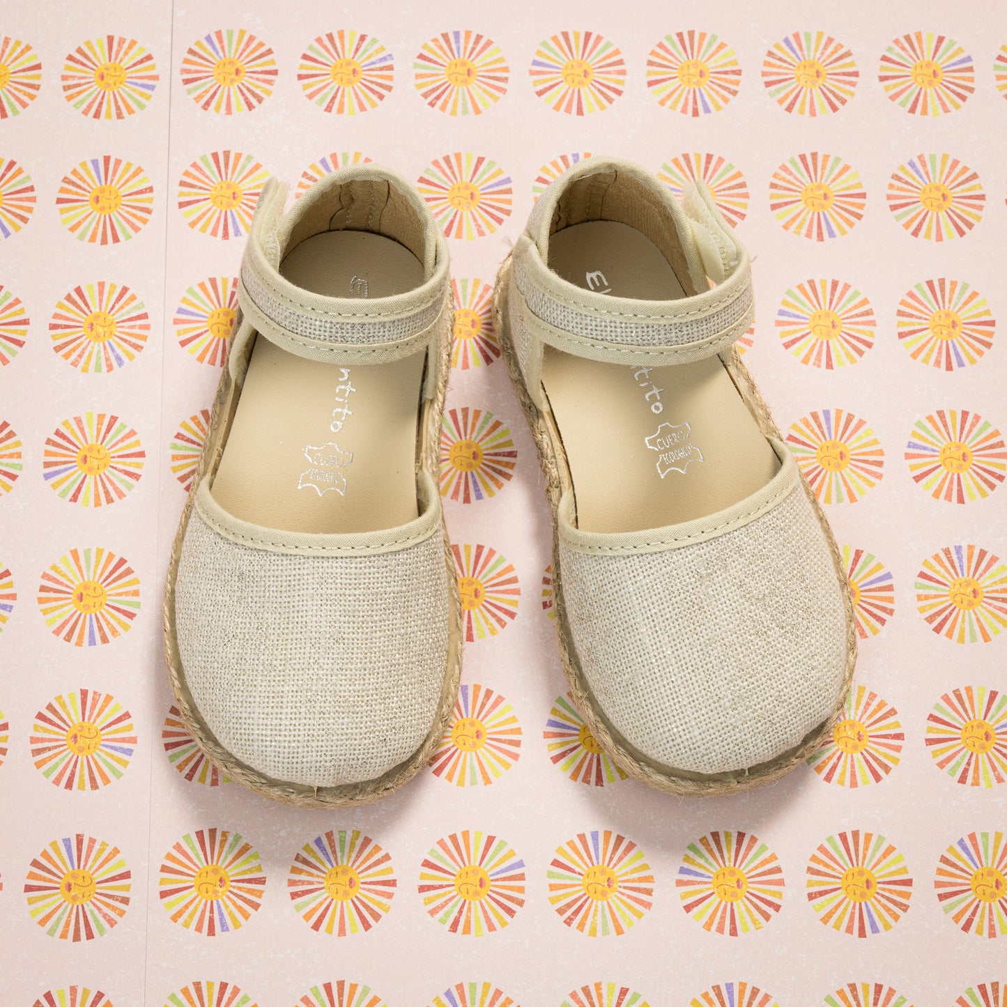 Metallic white linen toddler espadrille sandals with ankle strap and rounded toes on patterned background.