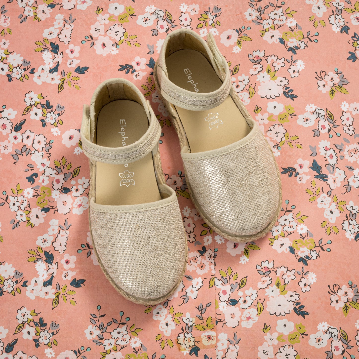 Metallic white linen espadrille sandals for girls with ankle straps on floral background.