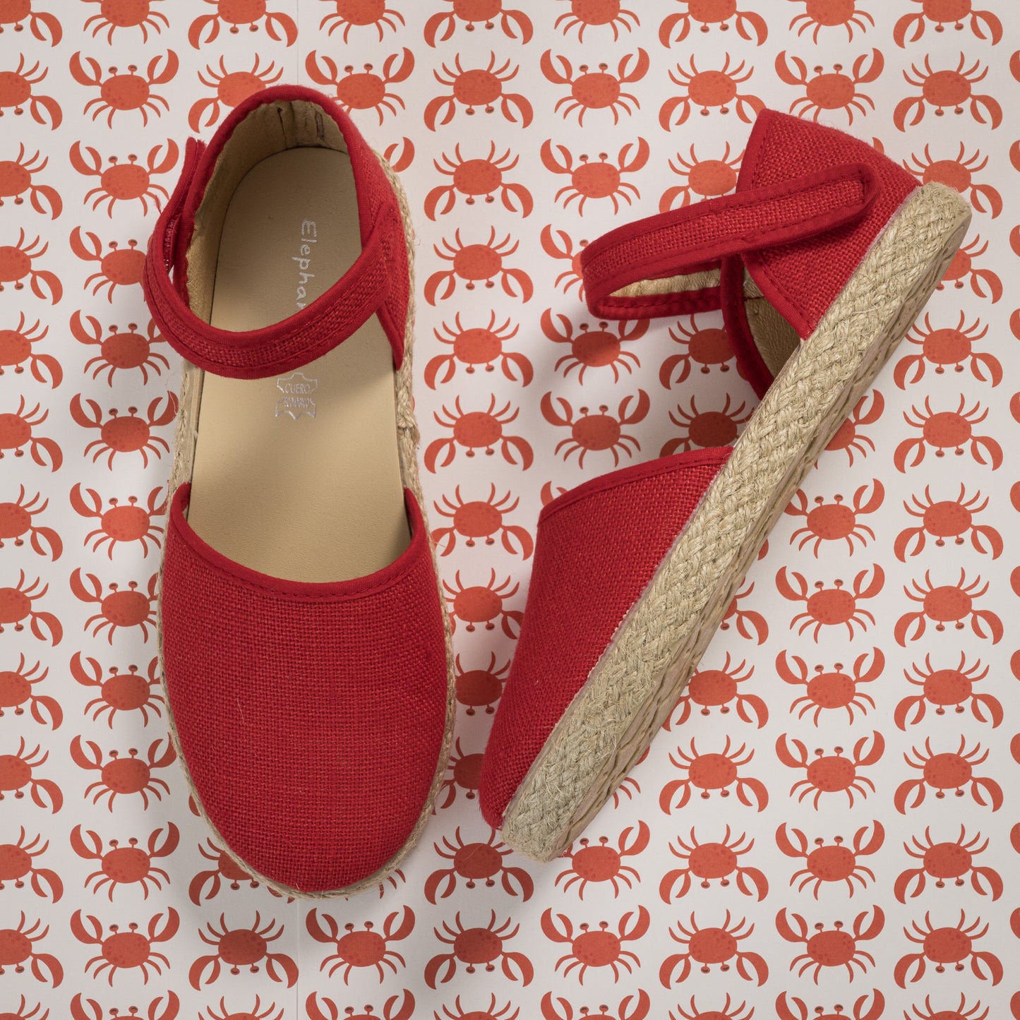 Red linen espadrille with ankle strap and jute sole on crab patterned background.