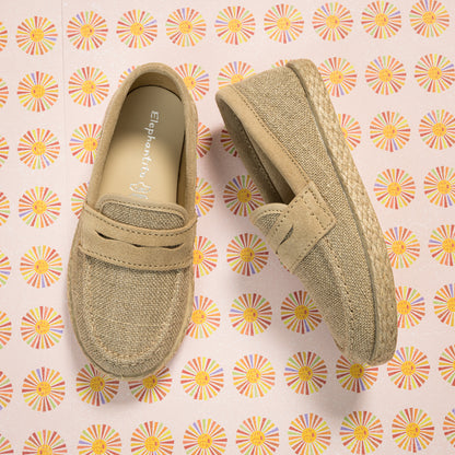 Beige toddler loafer espadrilles with woven jute sole and suede-like upper on floral background.