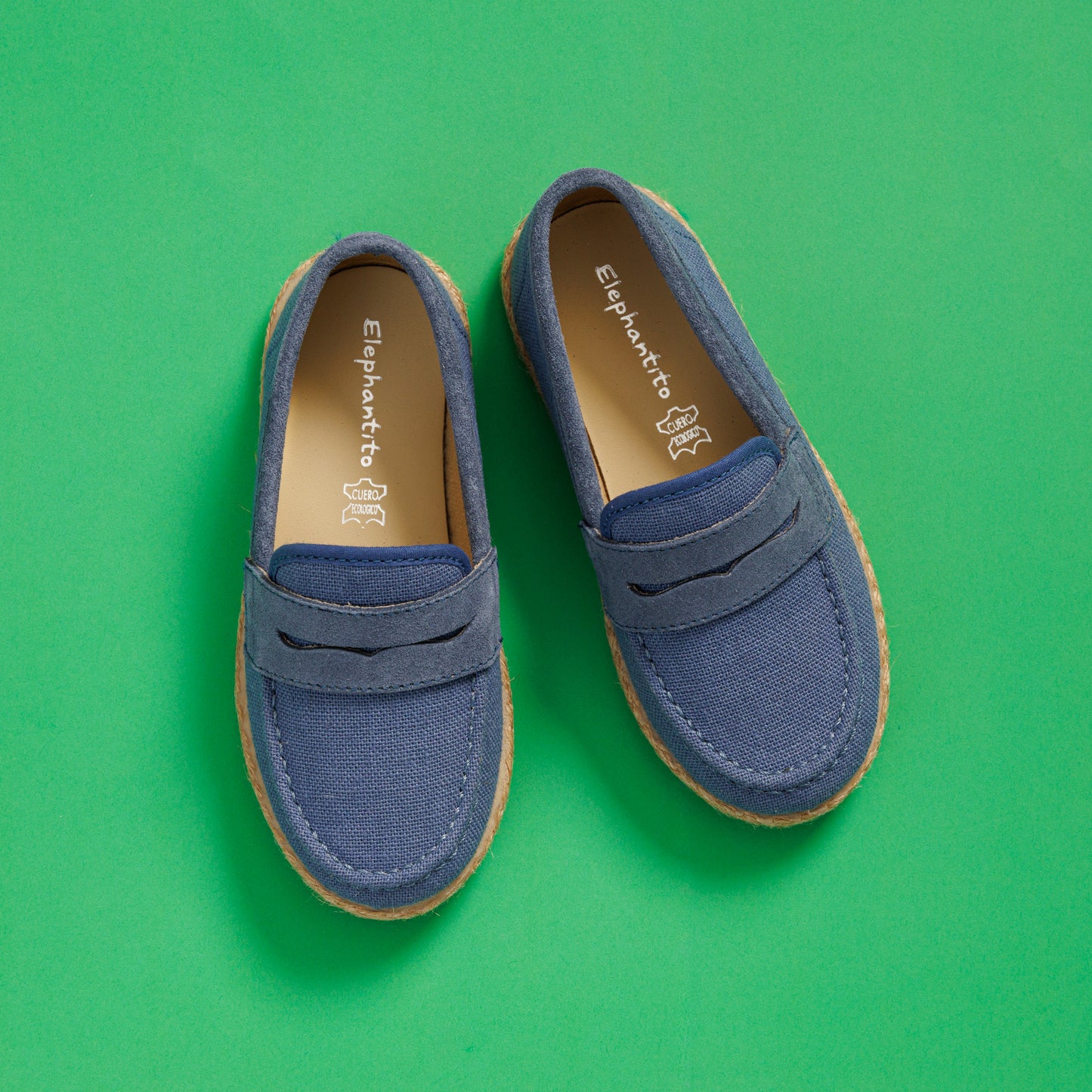 Elephantito - Blue toddler loafer espadrilles with tan stitching and natural jute sole on green background.