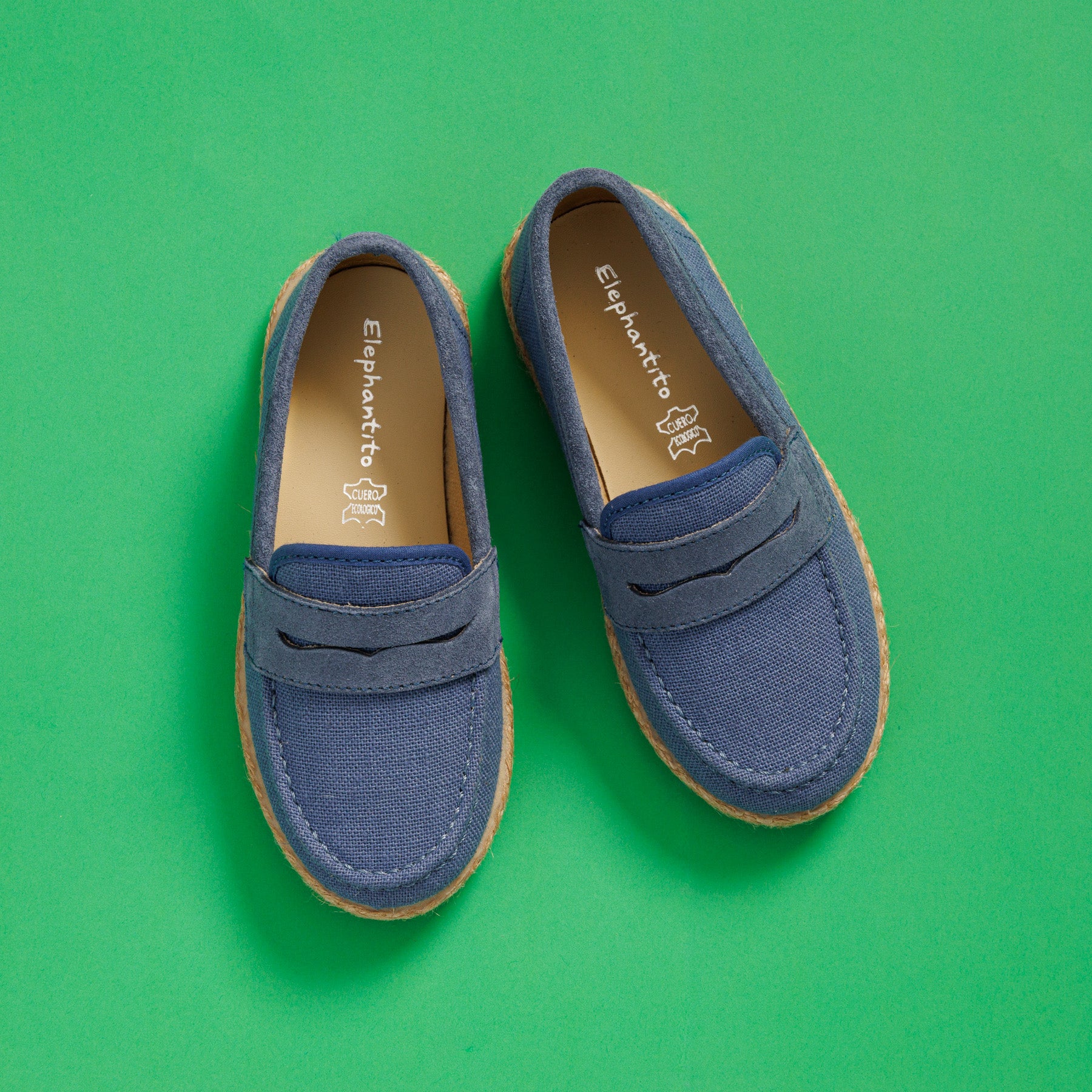 Elephantito - Blue toddler loafer espadrilles with tan stitching and natural jute sole on green background.