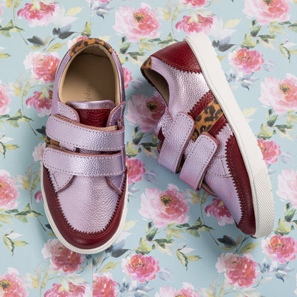 Kids' metallic carnation pink sneakers with double velcro straps and leopard print accents on floral background.