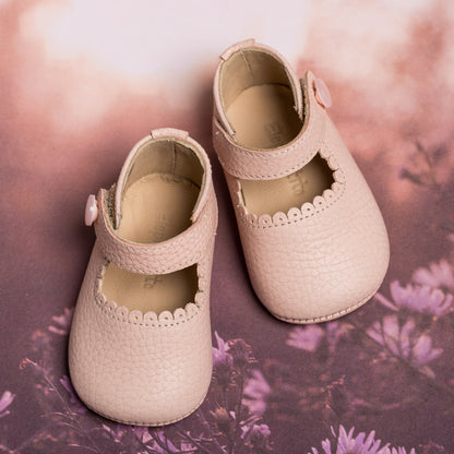 Soft pink textured leather baby Mary Jane shoes with scalloped edge and side button strap.