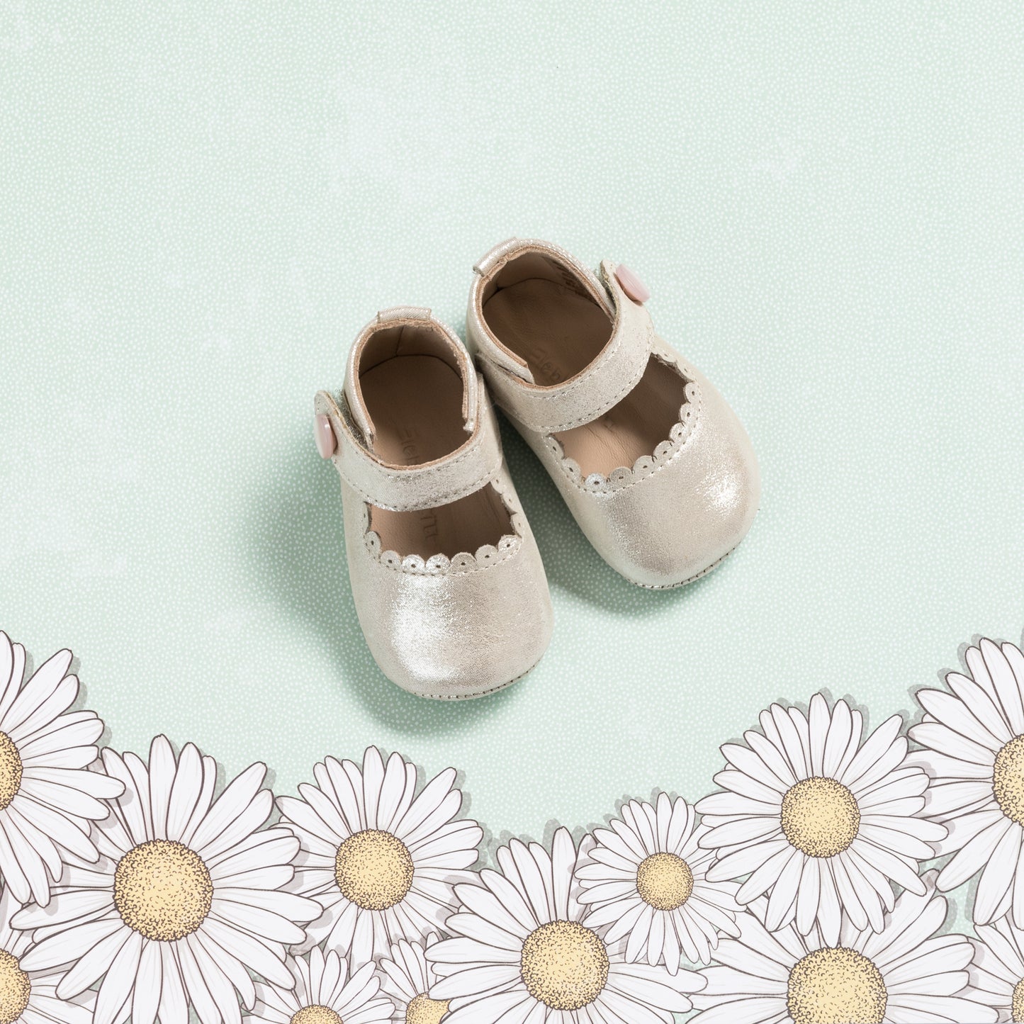 Soft pink baby Mary Jane shoes with scalloped edges and a velcro strap on a light green background.