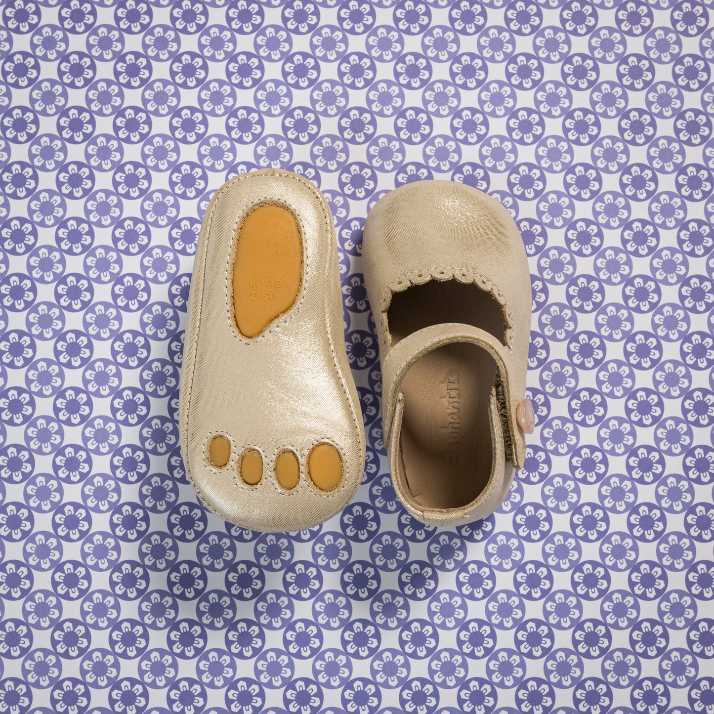 Soft cream-colored baby Mary Jane shoes with scalloped edges and a tan sole patch shaped like toes.
