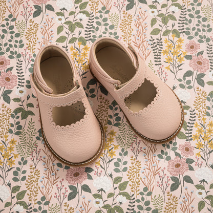 Pink leather Mary Jane shoes for toddlers with scalloped edges and velcro strap.