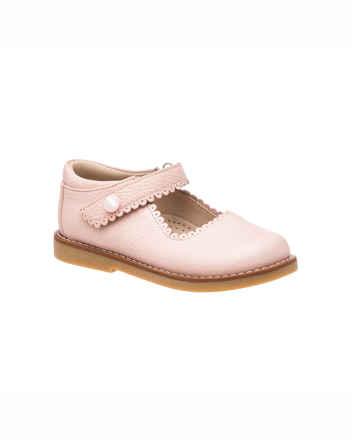 Pink leather Mary Jane shoe with scalloped edges and velcro strap on tan sole.
