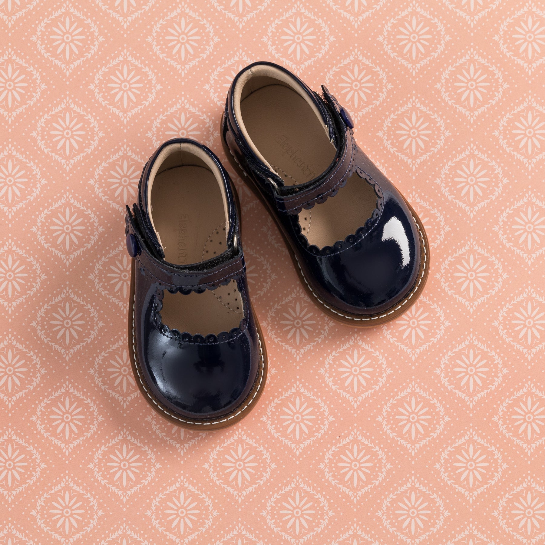 Toddler navy blue patent leather Mary Jane shoes with scalloped edges and Velcro strap.