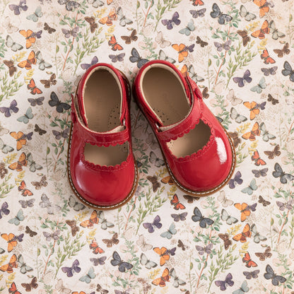 Toddler red patent leather Mary Jane shoes with scalloped edges and strap closures.