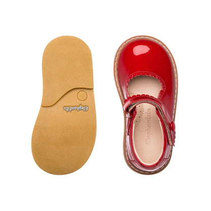 Toddler Mary Jane shoe in glossy red patent leather with scalloped edge and buckle strap, tan sole visible.