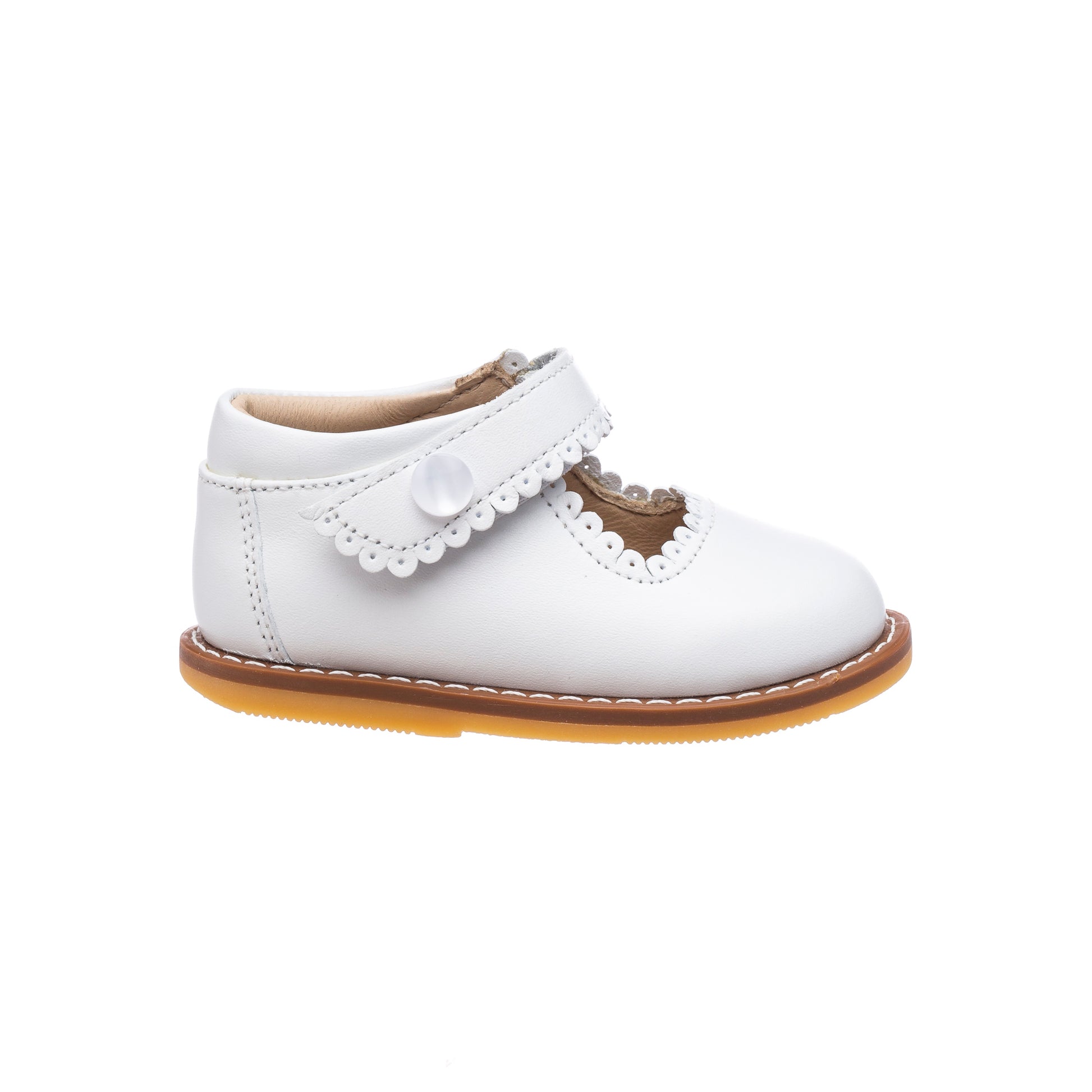 White toddler Mary Jane shoe with scalloped edges, heart-shaped cutout, and tan sole.