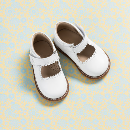 White leather Mary Jane shoes for girls with scalloped edges and brown sole.