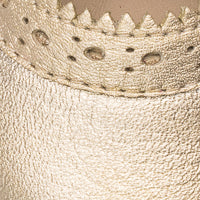 Close-up of gold textured leather baby Mary Jane shoe with scalloped edge detailing and perforations.