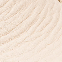 Cream-colored soft leather baby moccasin with textured stitching details.