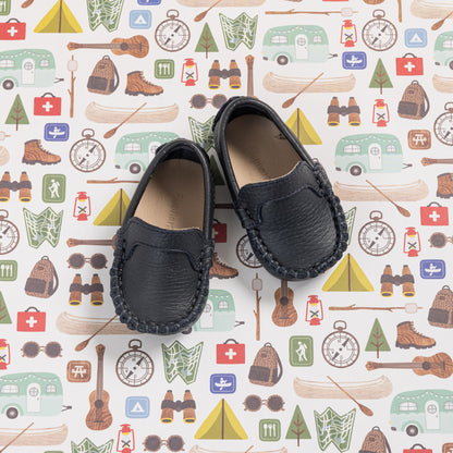 Navy blue baby moccasins with stitched detailing and soft leather lining on patterned background.