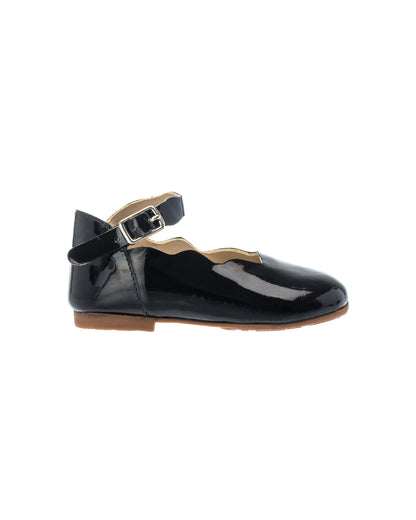 Black patent leather toddler flat with ankle strap and silver buckle, scalloped edges, and brown sole.