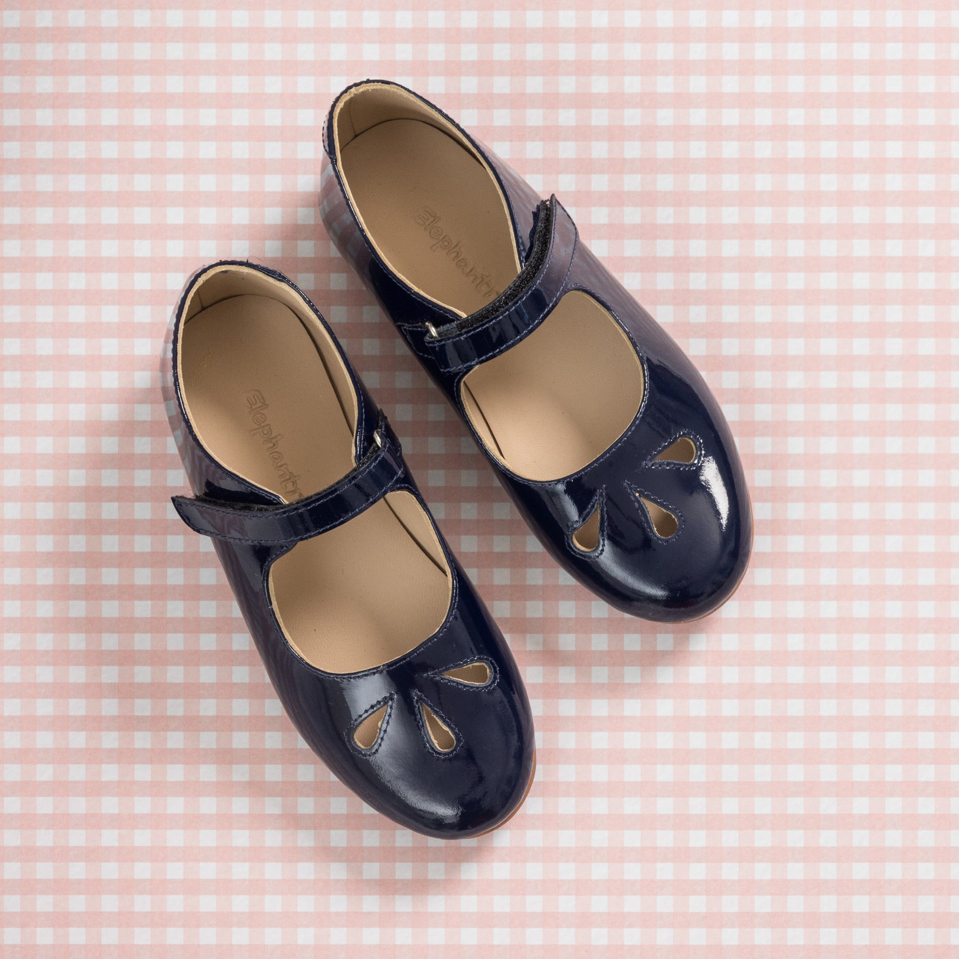 Glossy navy blue patent leather Mary Jane shoes with cutout details and ankle straps for girls.
