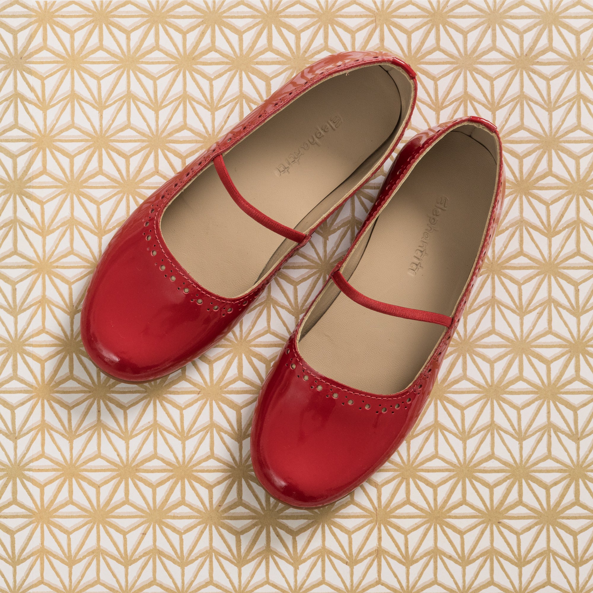 Red patent leather ballerina flats for girls with a thin strap across the top.