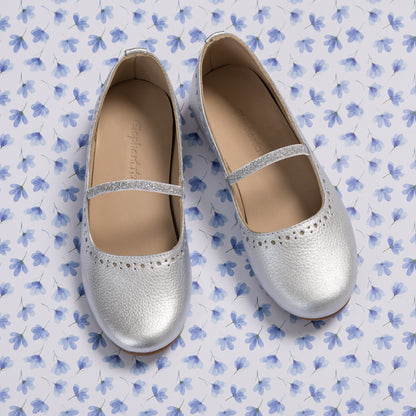 Silver toddler ballerina flats with perforated detailing and a thin elastic strap across the top.