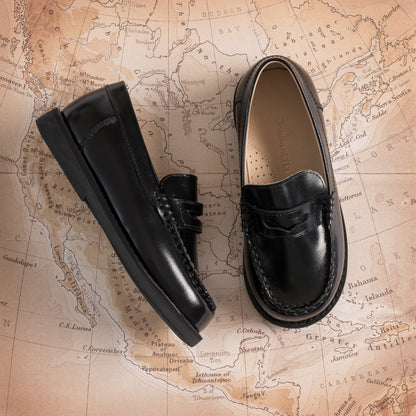 Black glossy leather boys moccasin loafers with penny strap and stitched detailing.