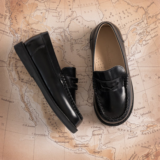 Black glossy leather boys moccasin loafers with penny strap and stitched detailing.