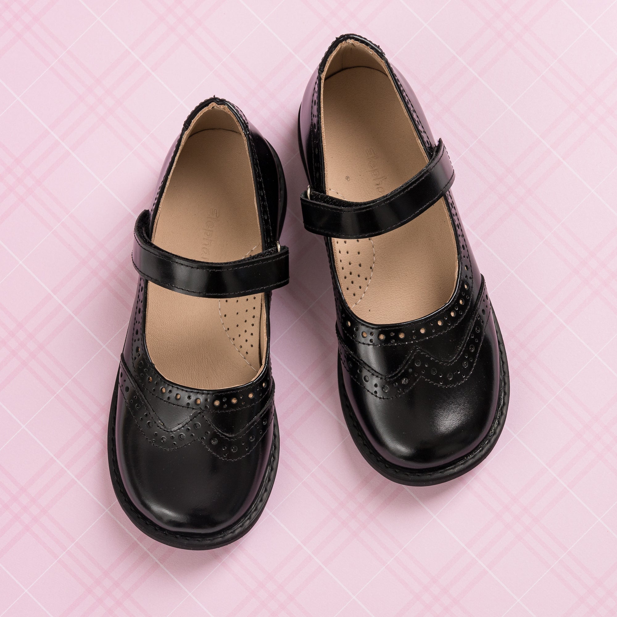 Black leather Mary Jane shoes for girls with brogue detailing and adjustable straps.