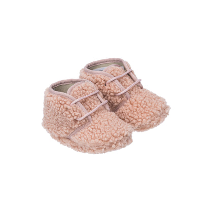 Pink shearling baby booties with soft textured exterior and front strap closure.