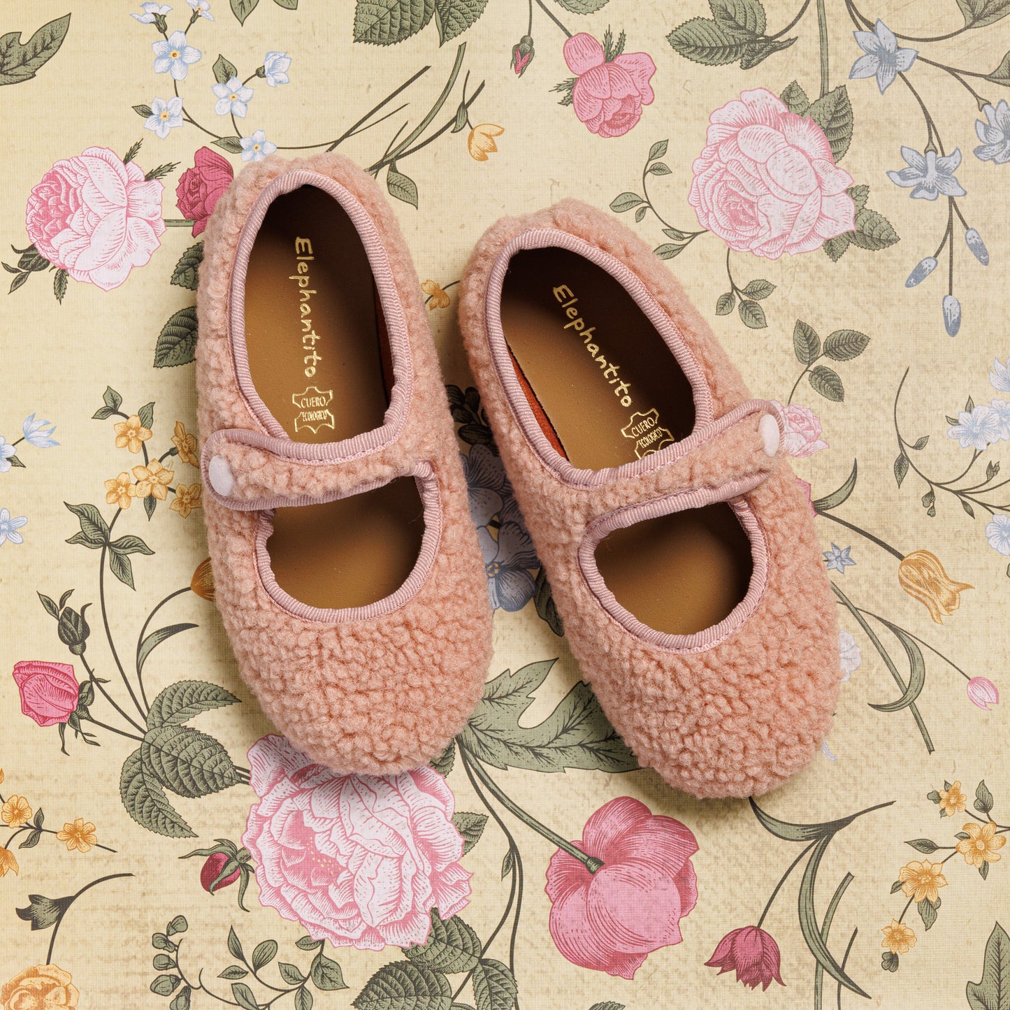Pink shearling Mary Jane shoes for toddlers with strap and rounded toe on floral background.