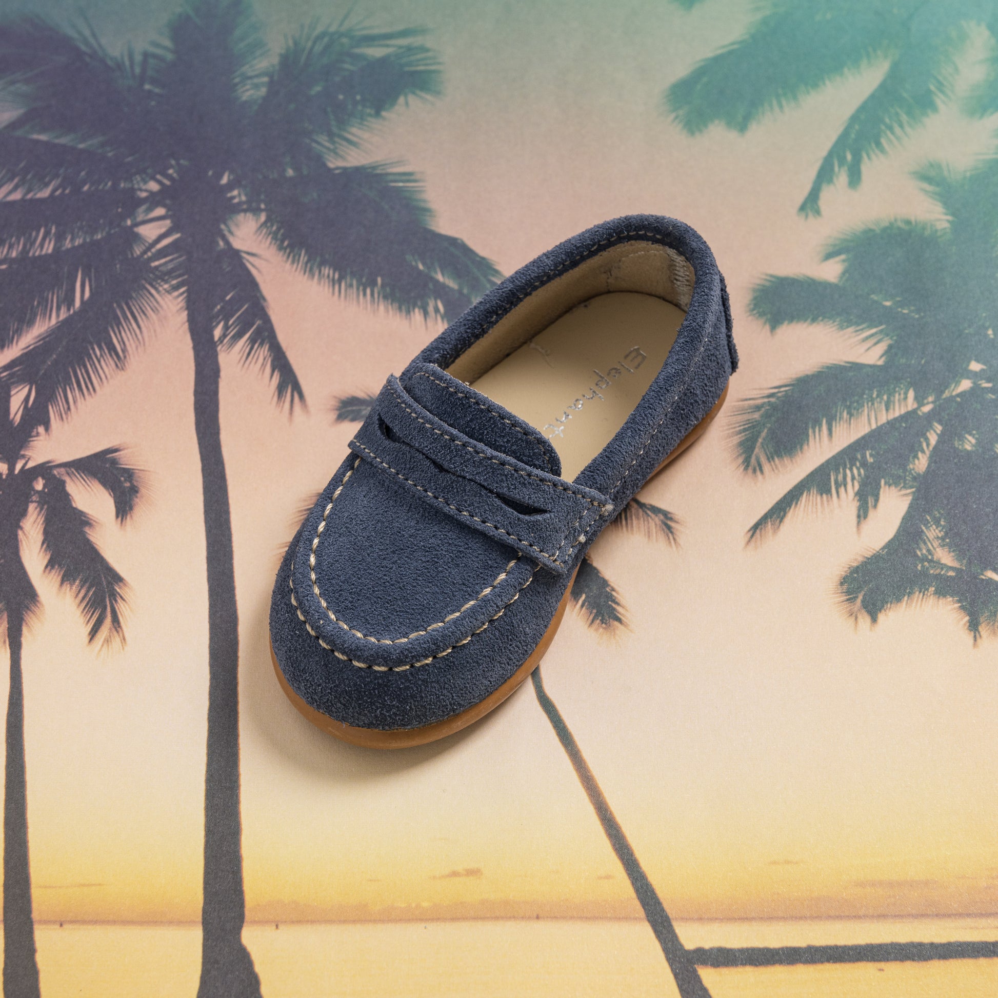 Navy blue suede penny loafer for toddlers with contrast stitching and penny strap on top.