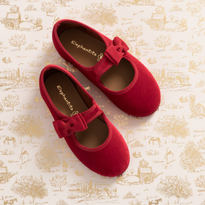 Red velvet Mary Jane shoes with a bow detail on the strap for toddlers and little kids.
