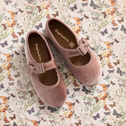 Pink velvet Mary Jane shoes for toddlers with a bow on the strap and rounded toes.