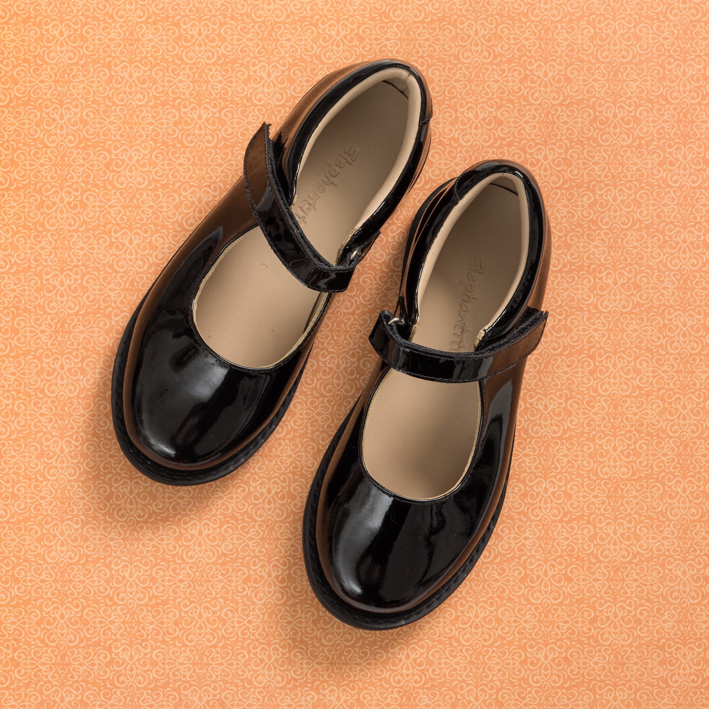 Black patent leather Mary Jane shoes with a round toe and Velcro strap for kids.