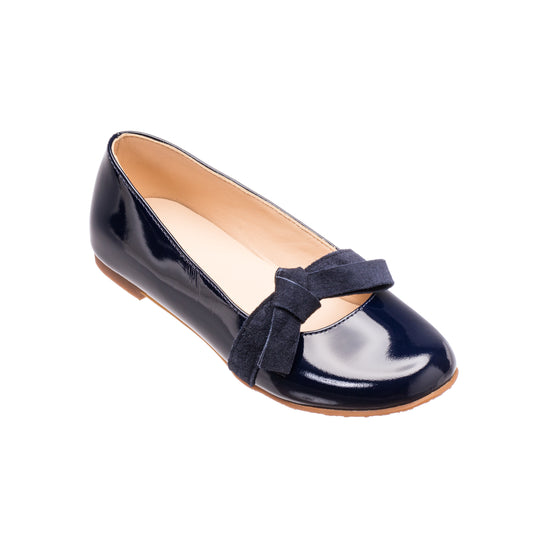 Navy blue patent leather flat with suede bow detail and tan sole.