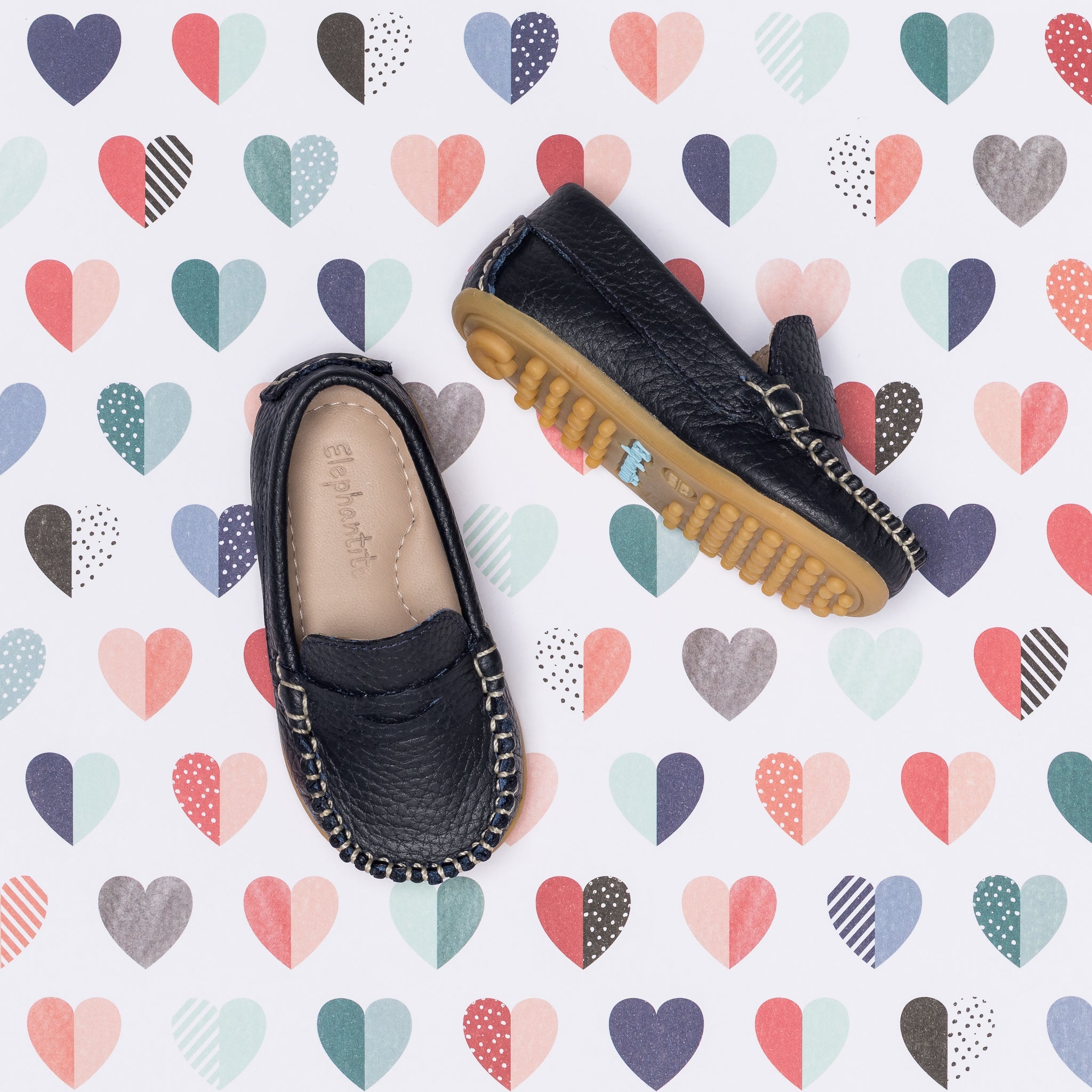 Navy blue toddler moccasin shoes with stitched detailing and tan rubber soles.