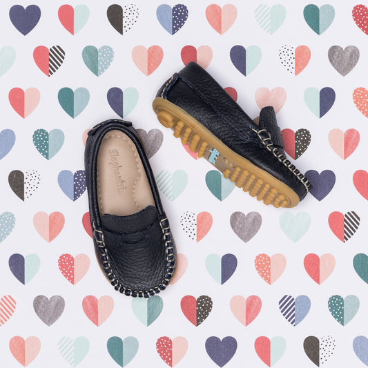 Navy blue toddler moccasin shoes with stitched detailing and tan rubber soles.