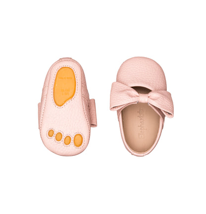 Pink baby ballerina shoe with large bow and flexible sole featuring orange toe grips.