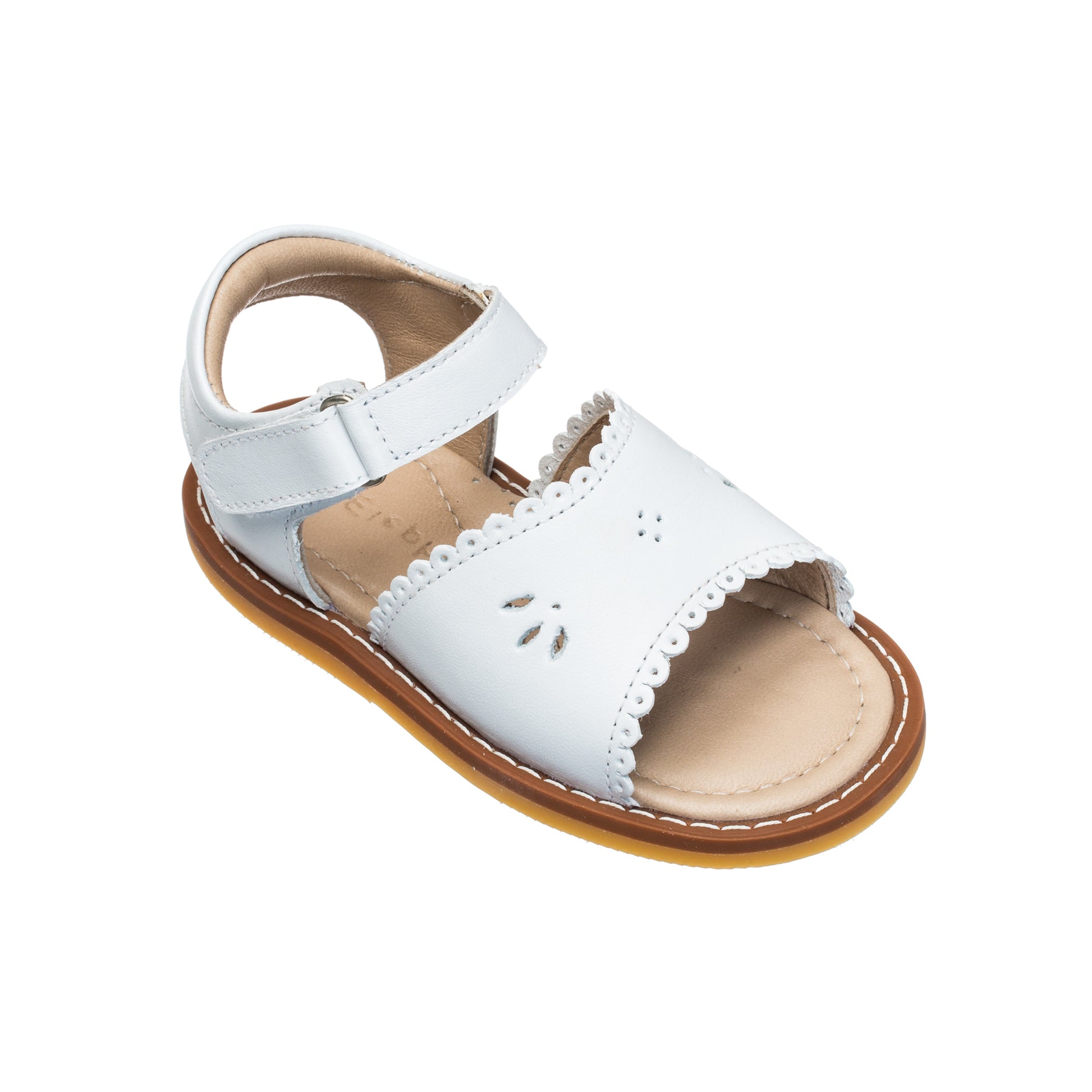 White toddler sandal with scalloped edge, cutout detailing, adjustable ankle strap, and tan sole.