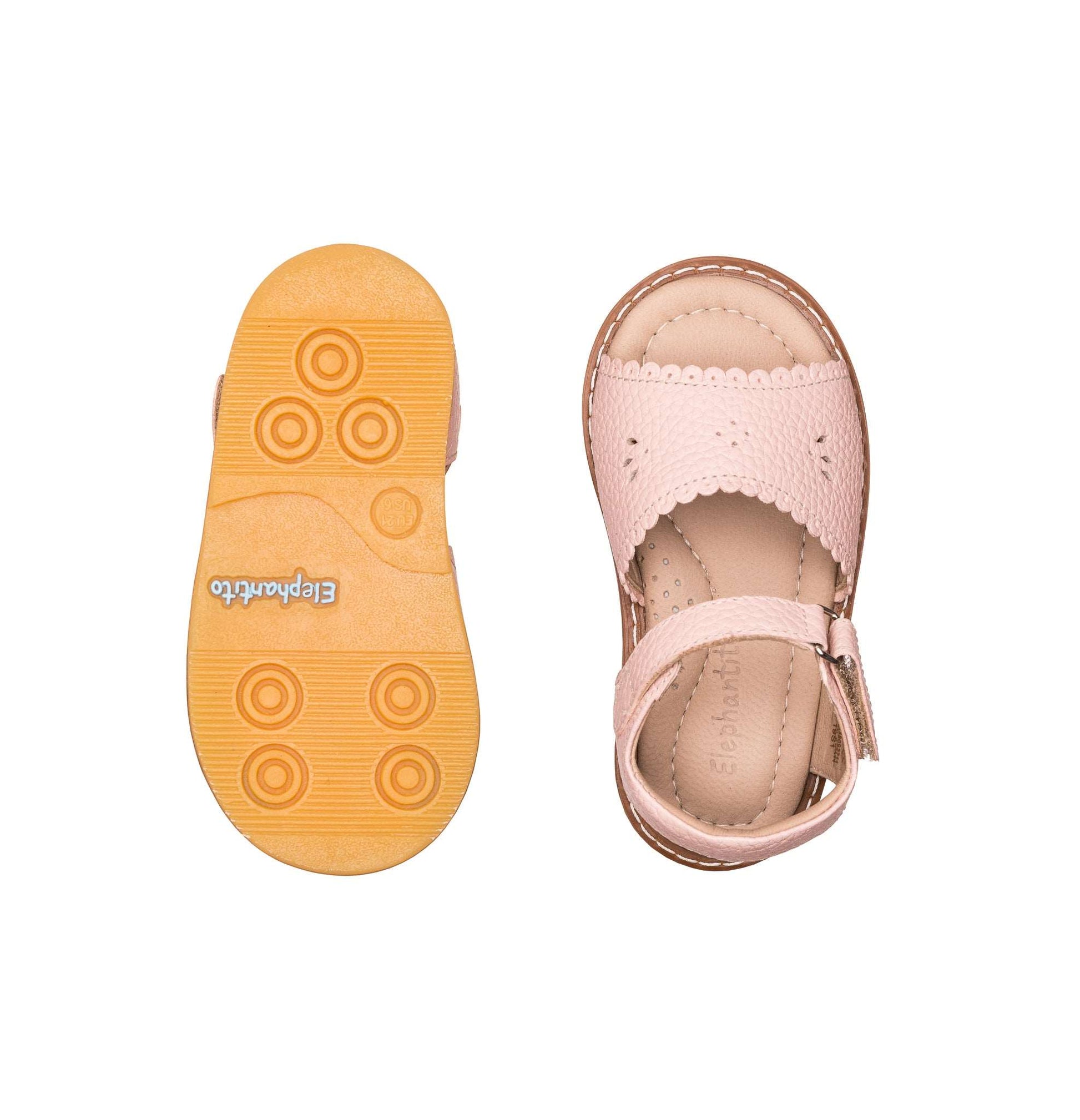 Pink toddler sandal with scalloped edges and adjustable ankle strap, rubber sole with circular grips.