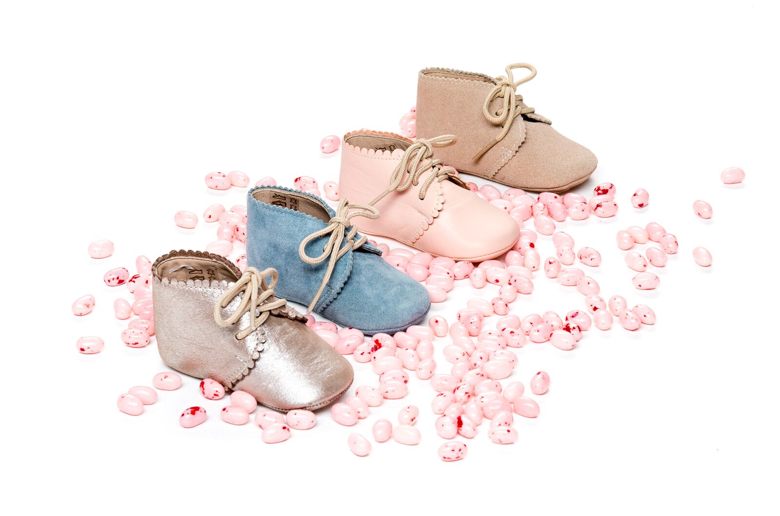 Four pairs of baby booties in beige, pink, blue, and silver with scalloped edges and lace-up fronts, displayed with small.