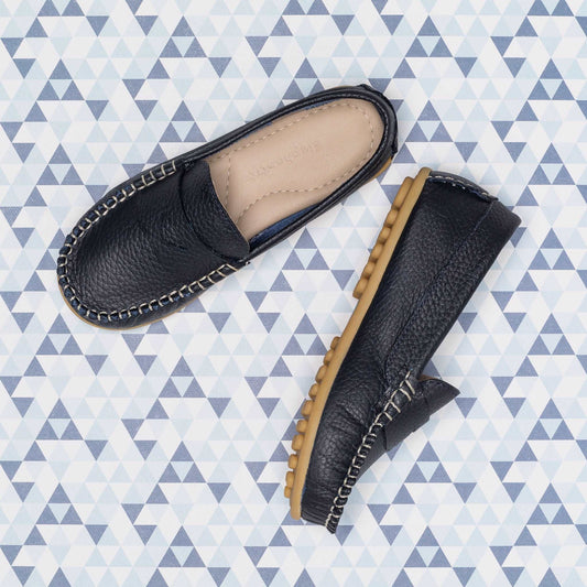 Navy blue boys' leather loafers with tan rubber sole and contrast stitching detail.